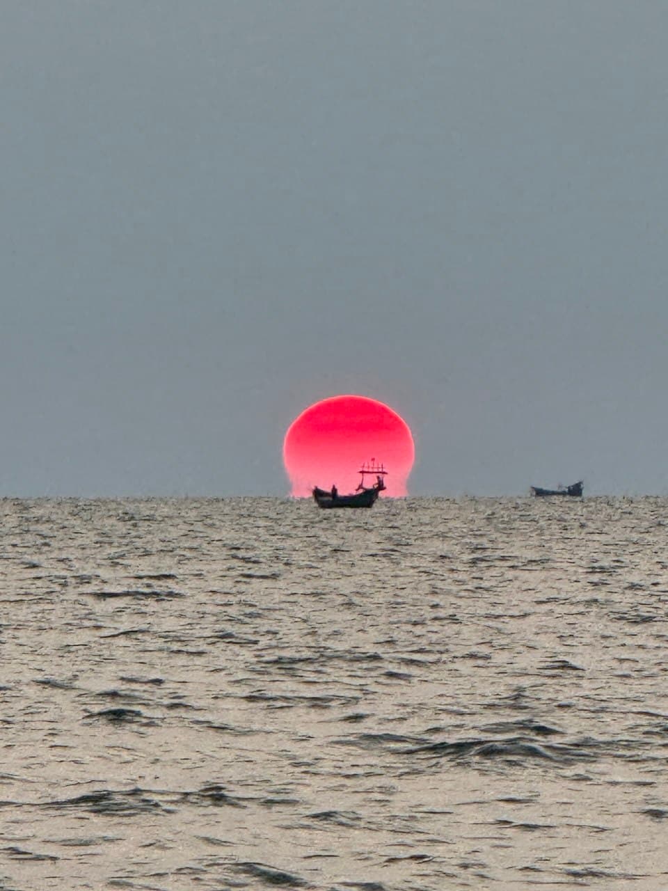 Boat silhouetted against a red Kampot sunset